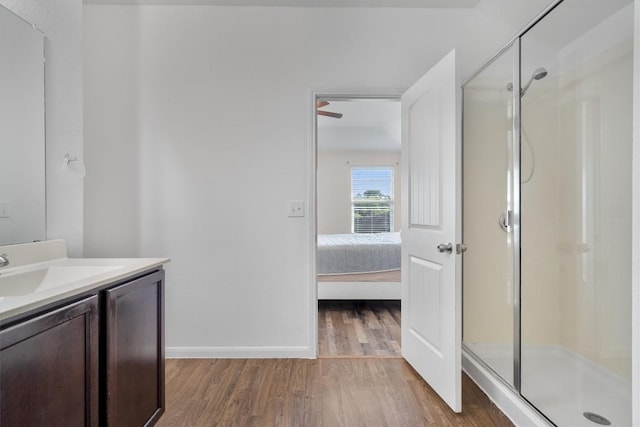 ensuite bathroom featuring wood finished floors, a stall shower, vanity, and baseboards