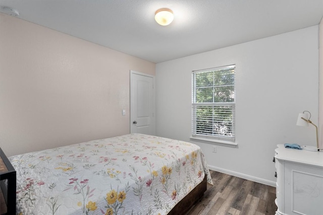 bedroom with dark wood finished floors and baseboards