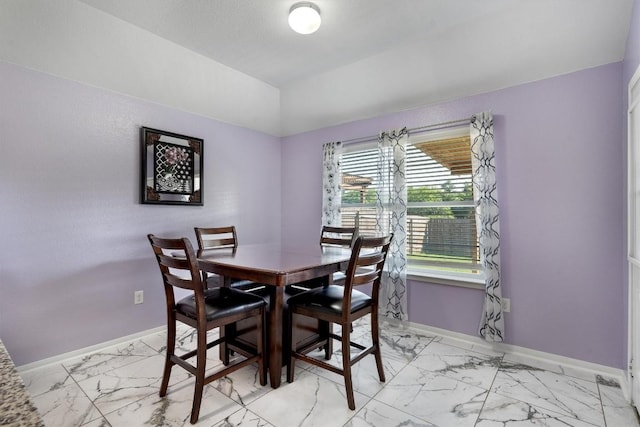 dining area with light marble finish floors, baseboards, and vaulted ceiling