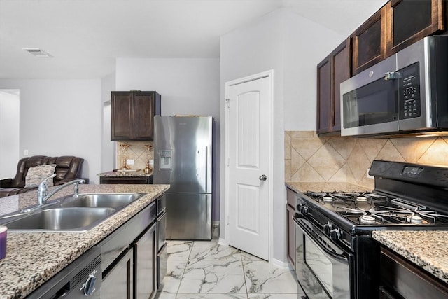 15013 Roody Ln, Austin, TX 78725 - kitchen with stainless steel appliances, a sink, light marble finish flooring, dark brown cabinets, and tasteful backsplash