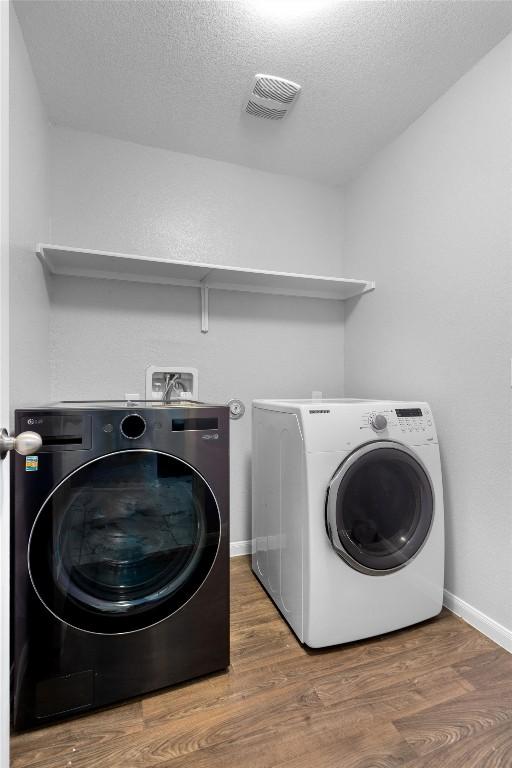 15013 Roody Ln, Austin, TX 78725 - laundry room featuring independent washer and dryer, wood finished floors, baseboards, and a textured ceiling