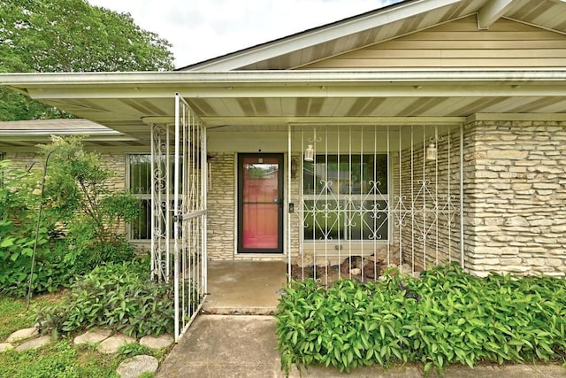 view of exterior entry featuring covered porch and stone siding