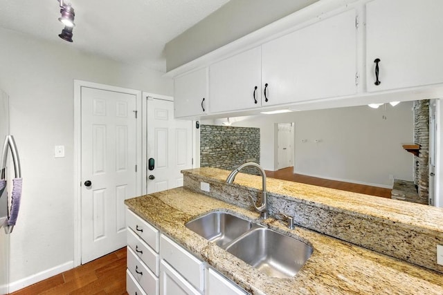 kitchen featuring a sink, dark wood-style flooring, white cabinets, and light stone counters
