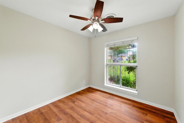 empty room with baseboards, light wood finished floors, and ceiling fan
