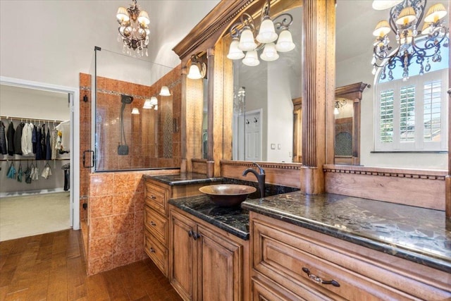 12013 Tarraza Ct, Austin, TX 78732 - bathroom featuring a chandelier, vanity, a spacious closet, a tile shower, and wood finished floors