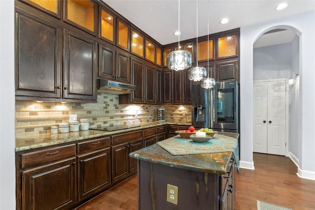 12013 Tarraza Ct, Austin, TX 78732 - kitchen with under cabinet range hood, arched walkways, stainless steel fridge with ice dispenser, stone countertops, and backsplash