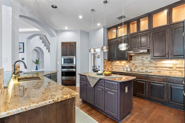12013 Tarraza Ct, Austin, TX 78732 - kitchen featuring a sink, appliances with stainless steel finishes, a center island, dark wood finished floors, and decorative backsplash