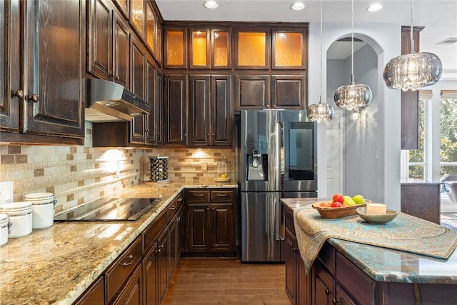 12013 Tarraza Ct, Austin, TX 78732 - kitchen with stainless steel refrigerator with ice dispenser, under cabinet range hood, black electric stovetop, light stone countertops, and wood finished floors