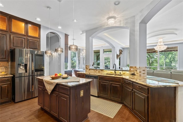 12013 Tarraza Ct, Austin, TX 78732 - kitchen featuring appliances with stainless steel finishes, a sink, decorative backsplash, light stone counters, and recessed lighting