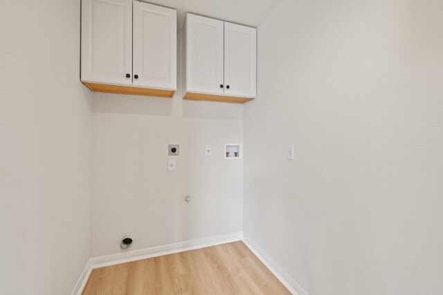 laundry area featuring electric dryer hookup, cabinet space, washer hookup, light wood-style flooring, and baseboards