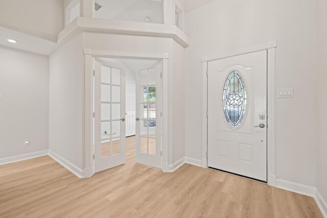 entrance foyer with light wood-style flooring, baseboards, and french doors