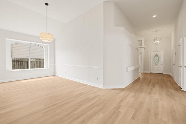 foyer featuring light wood-style floors, a chandelier, baseboards, and recessed lighting