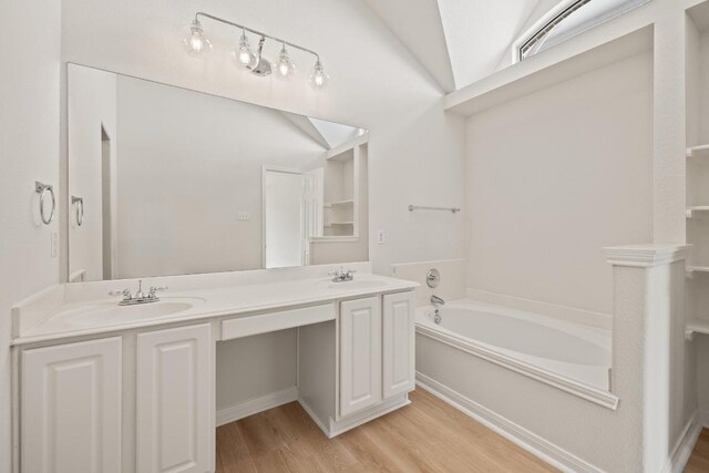 full bath with wood finished floors, double vanity, a garden tub, and lofted ceiling