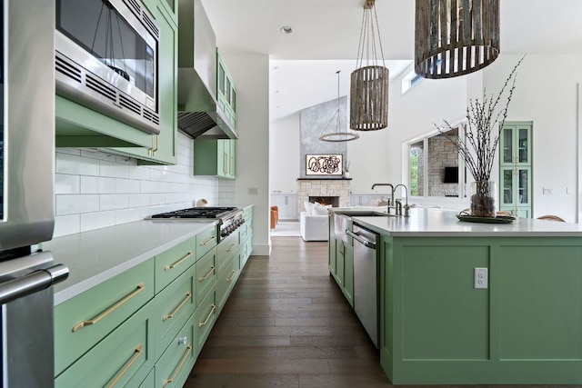 13213 Meridian Park Blvd, Austin, TX 78739 - kitchen with green cabinets, a fireplace, appliances with stainless steel finishes, wall chimney exhaust hood, and dark wood-style floors