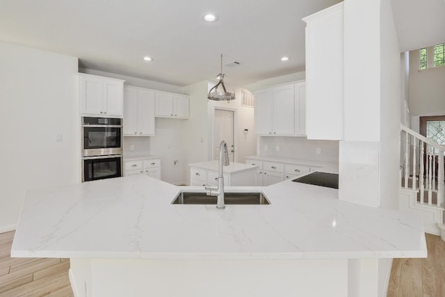 12207 Carlsbad Dr, Austin, TX 78738 - kitchen featuring double oven, a peninsula, light wood-type flooring, light stone countertops, and recessed lighting