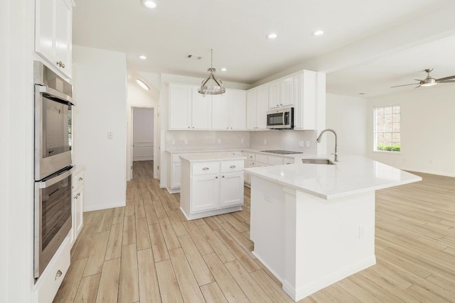 kitchen with stainless steel appliances, a sink, light wood-style flooring, a peninsula, and recessed lighting