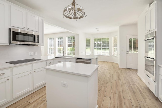 12207 Carlsbad Dr, Austin, TX 78738 - kitchen featuring stainless steel appliances, a chandelier, light wood finished floors, a peninsula, and a kitchen island