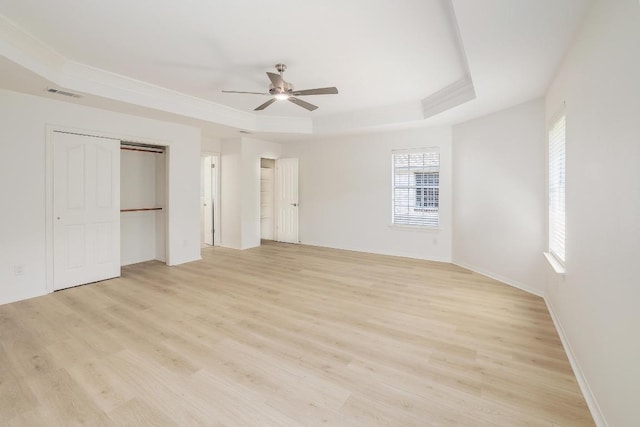 unfurnished bedroom with a raised ceiling, light wood-style flooring, baseboards, ceiling fan, and crown molding