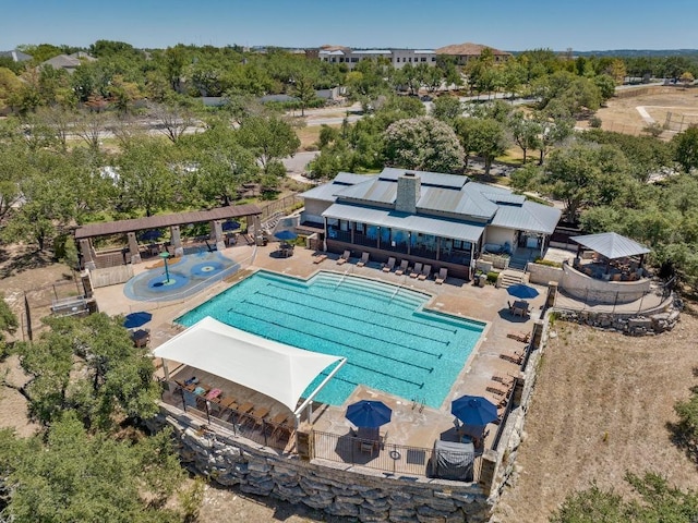 community pool with a patio, fence, and view of scattered trees
