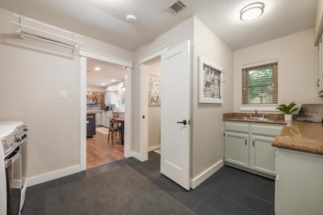 10305 Pickfair Dr, Austin, TX 78750 - washroom with washing machine and clothes dryer, dark tile patterned flooring, and a textured ceiling