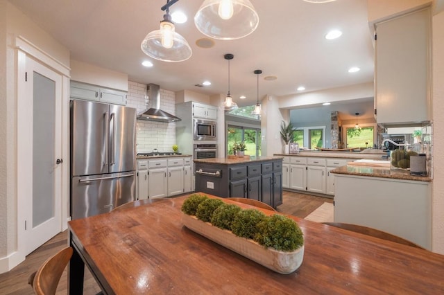 10305 Pickfair Dr, Austin, TX 78750 - kitchen featuring appliances with stainless steel finishes, wall chimney exhaust hood, decorative backsplash, dark wood-style floors, and hanging light fixtures