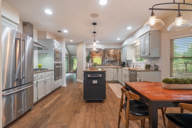 10305 Pickfair Dr, Austin, TX 78750 - kitchen featuring appliances with stainless steel finishes, decorative backsplash, dark wood-type flooring, decorative light fixtures, and recessed lighting
