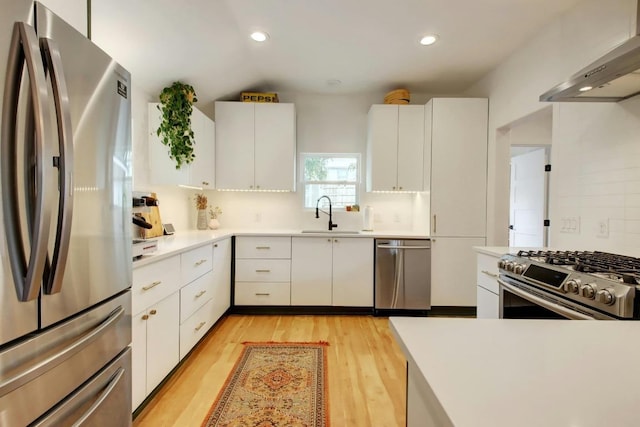 2000 E 8th St, Austin, TX 78702 - kitchen with appliances with stainless steel finishes, a sink, range hood, light wood-style floors, and white cabinets