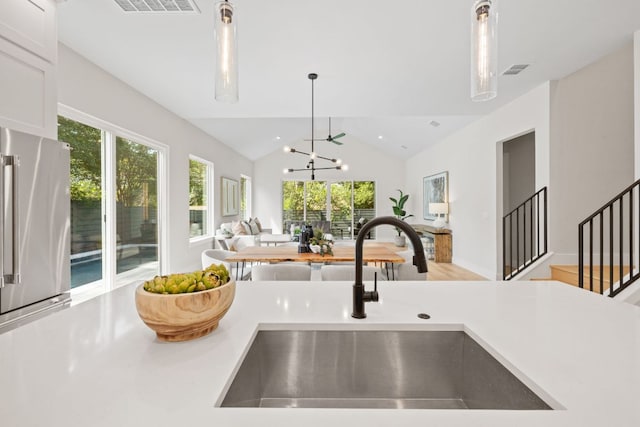 kitchen with a sink, open floor plan, light countertops, plenty of natural light, and vaulted ceiling
