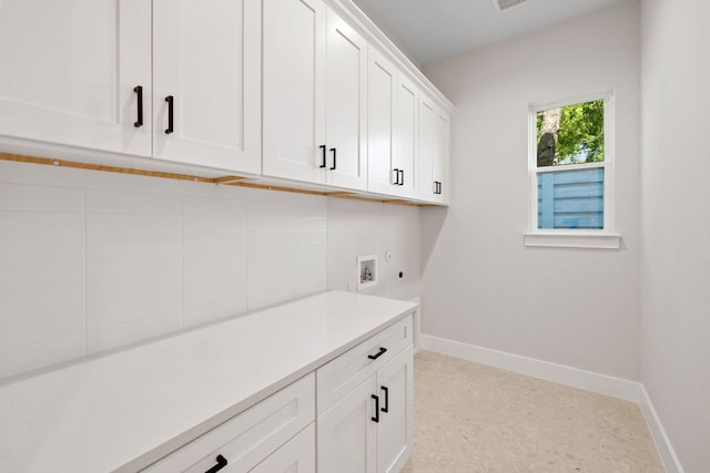 clothes washing area featuring cabinet space, baseboards, and washer hookup