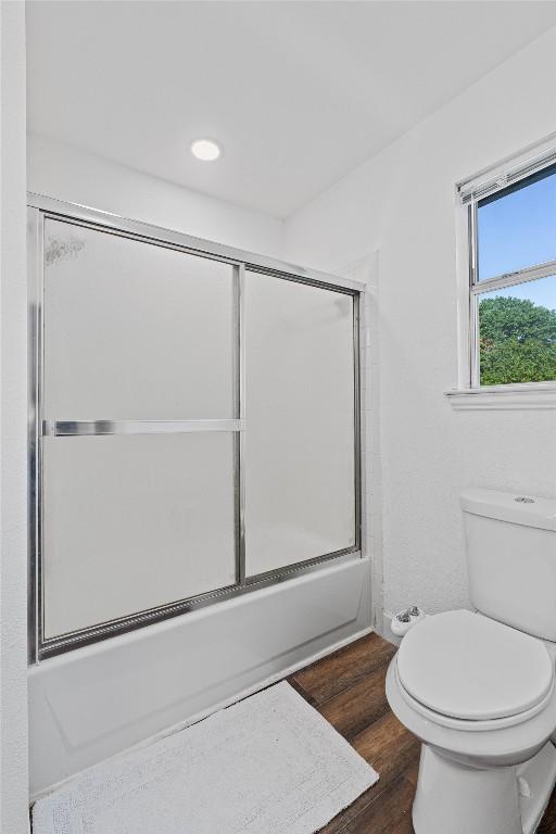 full bath featuring toilet, wood finished floors, bath / shower combo with glass door, and recessed lighting