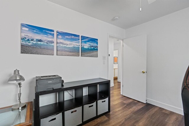 home office with dark wood-type flooring and baseboards