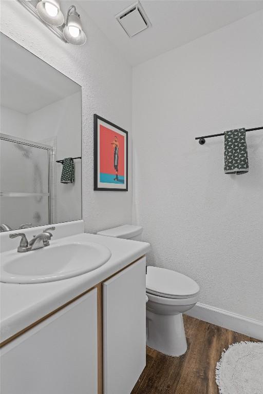 full bathroom with an enclosed shower, wood finished floors, vanity, toilet, and baseboards