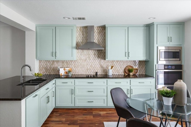 89 Jan Ln, Georgetown, TX 78626 - kitchen with appliances with stainless steel finishes, a sink, wall chimney exhaust hood, dark wood-style floors, and a peninsula