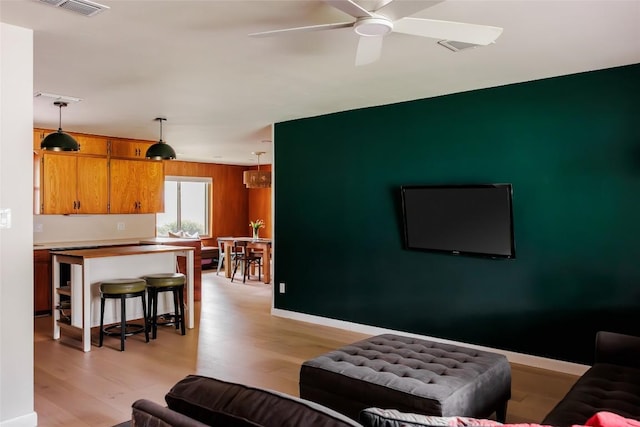 1805 Northridge Dr, Austin, TX 78723 - living area featuring light wood-style floors, wood walls, a ceiling fan, and baseboards