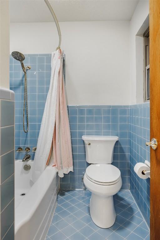 1805 Northridge Dr, Austin, TX 78723 - full bathroom featuring a wainscoted wall, toilet, shower / bath combo with shower curtain, tile patterned flooring, and tile walls