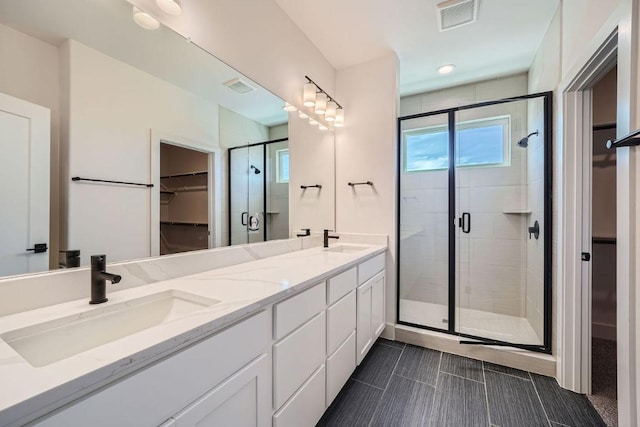 full bath featuring a shower stall, a spacious closet, plenty of natural light, and double vanity