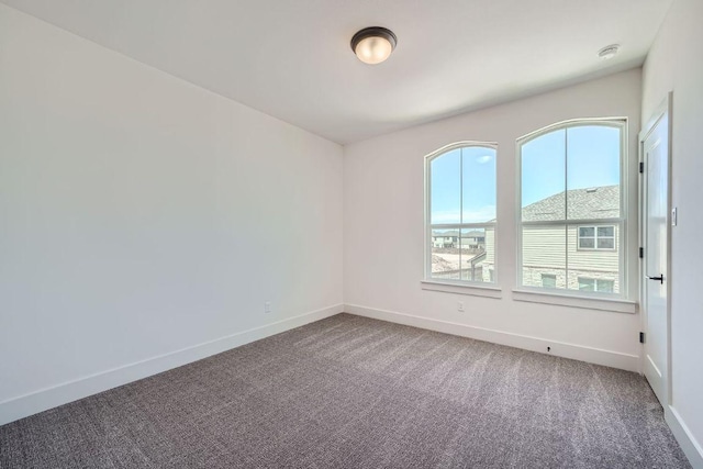 carpeted spare room featuring baseboards and a smoke detector