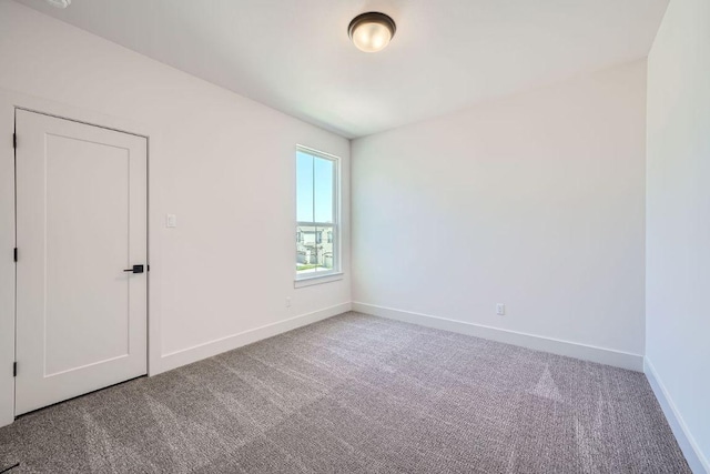 carpeted spare room featuring baseboards