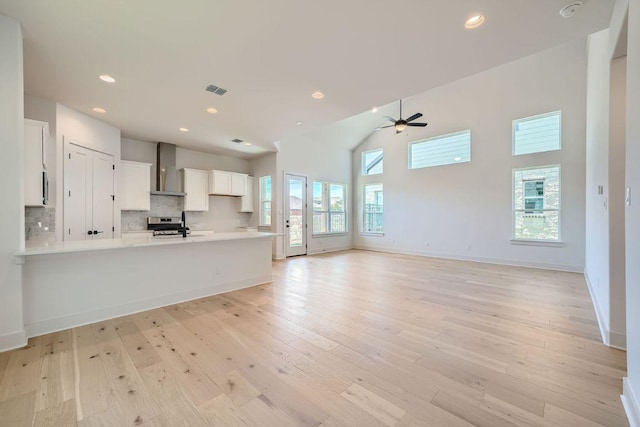 kitchen featuring a peninsula, a ceiling fan, light countertops, white cabinetry, and light wood finished floors