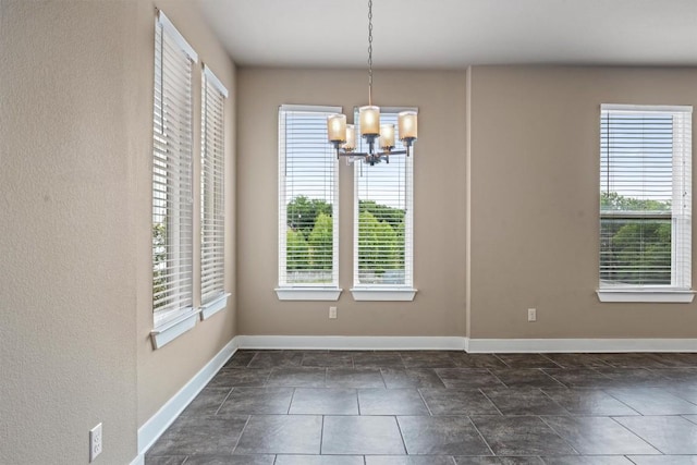 2621 Witsome Loop, Austin, TX 78741 - unfurnished dining area featuring a chandelier, baseboards, and dark stone finish floors