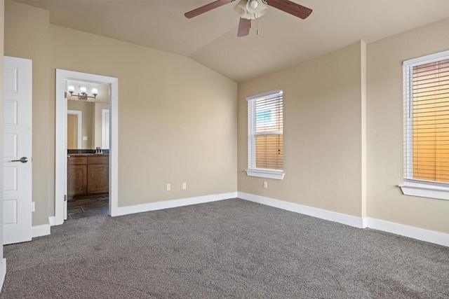 2621 Witsome Loop, Austin, TX 78741 - unfurnished bedroom featuring dark carpet, baseboards, vaulted ceiling, connected bathroom, and ceiling fan