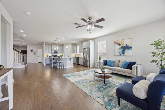 living room with dark wood finished floors, ceiling fan, stairway, recessed lighting, and baseboards