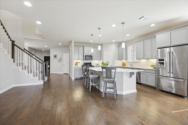 1716 Elaina Loop, Leander, TX 78641 - kitchen with stainless steel appliances, gray cabinets, a breakfast bar, recessed lighting, and a kitchen island