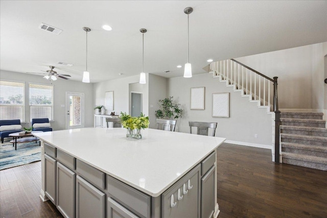 kitchen featuring gray cabinets, open floor plan, dark wood-style floors, a kitchen island, and light countertops