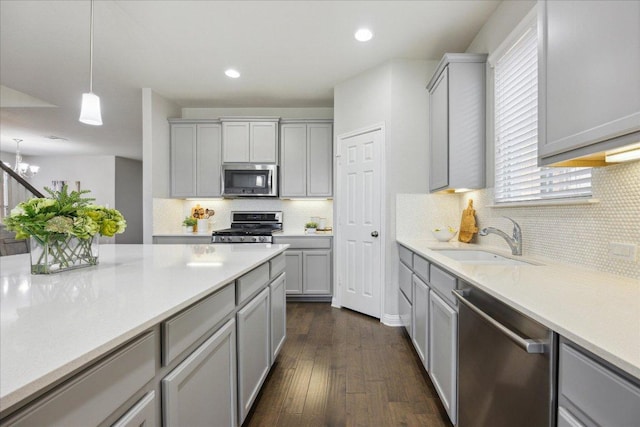 kitchen featuring appliances with stainless steel finishes, a sink, gray cabinets, backsplash, and recessed lighting