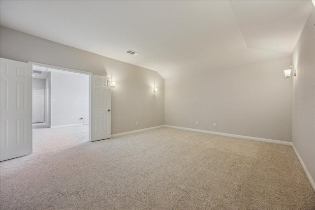 unfurnished room featuring lofted ceiling, light carpet, and baseboards