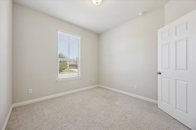 carpeted empty room featuring baseboards
