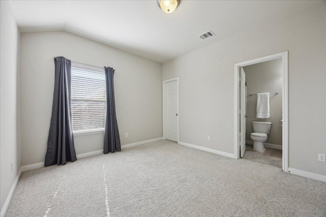 unfurnished bedroom with carpet flooring, vaulted ceiling, ensuite bathroom, and baseboards