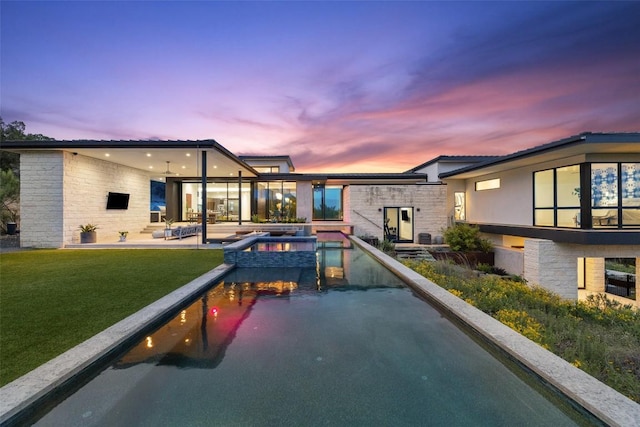 4202 Serene Hills Dr, Austin, TX 78738 - pool at dusk with a patio area, a pool with connected hot tub, and a yard