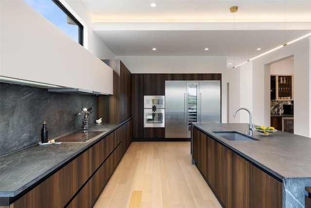 4202 Serene Hills Dr, Austin, TX 78738 - kitchen with modern cabinets, a sink, dark countertops, appliances with stainless steel finishes, and light wood-style floors